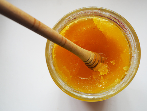 Caramelized honey dripping from a wooden spoon