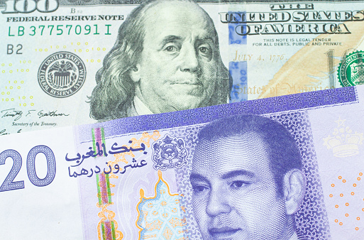 A macro image of a purple and white twenty dirham bank note from Morocco paired up with a blue, one hundred dollar bill from the United States.  Shot close up in macro.