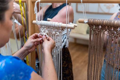Middle aged women making macrame of different colors