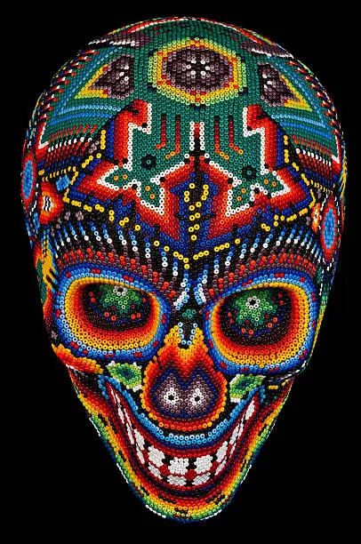 Colorful Beaded Skull from mexican traditional huichol bead art, symbol of the day of the dead,  isolated on black