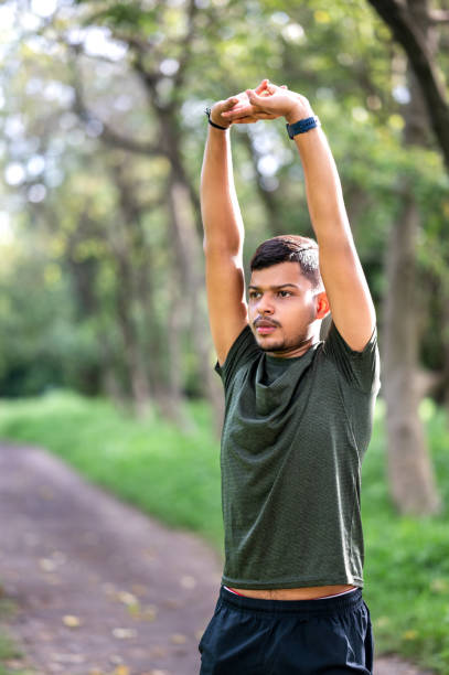 istock Shot of a young sporty man starting his exercise routine with stretching exercises 1590245109