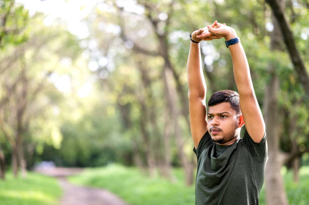 istock Shot of a young sporty man starting his exercise routine with stretching exercises 1590245127