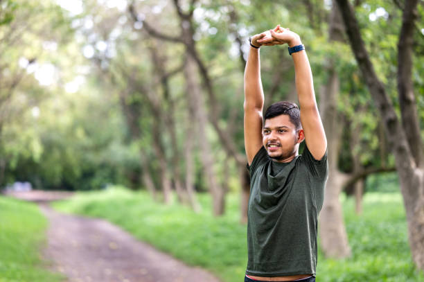 istock Shot of a young sporty man starting his exercise routine with stretching exercises 1590245145