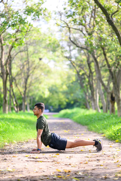 młody człowiek uprawiający jogę w pozie kobry lub bhujangasana - snake human hand color image cobra zdjęcia i obrazy z banku zdjęć