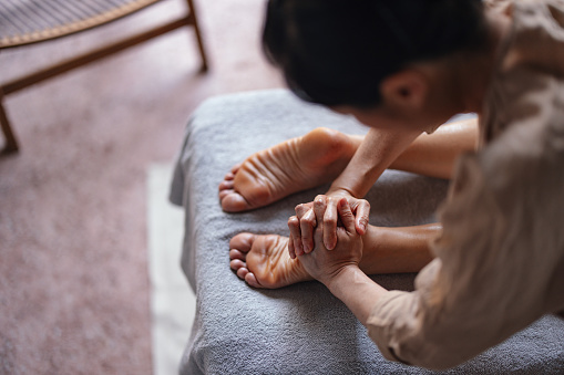 Close up shot of an unrecognizable female massage therapist massaging an anonymous woman's foot at the spa.