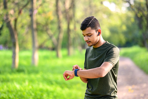 Outdoor image of Young sportsman checking his running time after a long run and morning exercise in morning