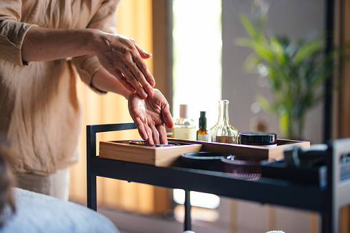 Close up shot of an unrecognizable woman's hands working with massage oil. She is applying oil ready to give a massage to a client.