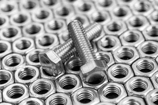 Bolts on the background of metal nuts. Close up.