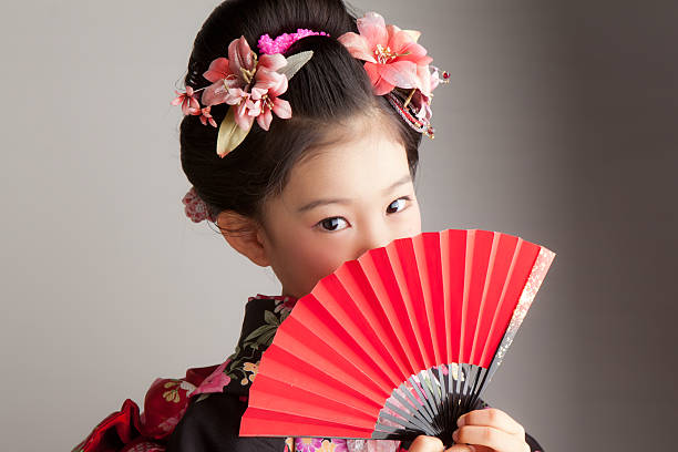 Young Japanese girl celebrating Shichi-Go-San with a red fan The girl dressed in the kimono. hand fan photos stock pictures, royalty-free photos & images