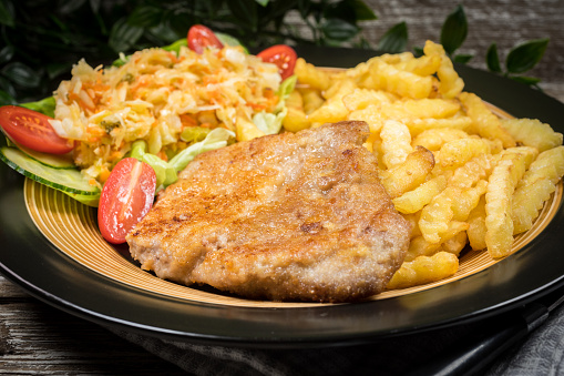 Traditional Polish dish: fried pork chop in breadcrumbs, served with fries and salad.