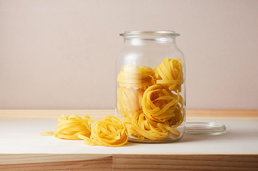 Uncooked tagliatelle pasta in a glass jar.
