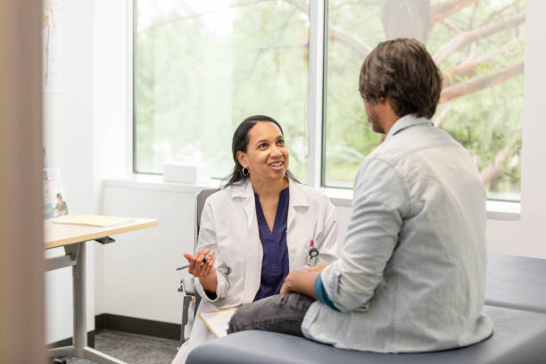 istock Cheerful female doctor interacts with unrecognizable male patient 1590330213