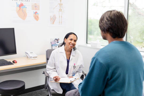 istock Mature doctor with chart smiles while listening to man 1590331249