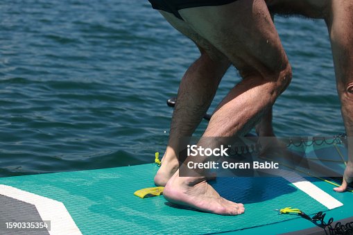 istock Man standing on surfboard 1590335354