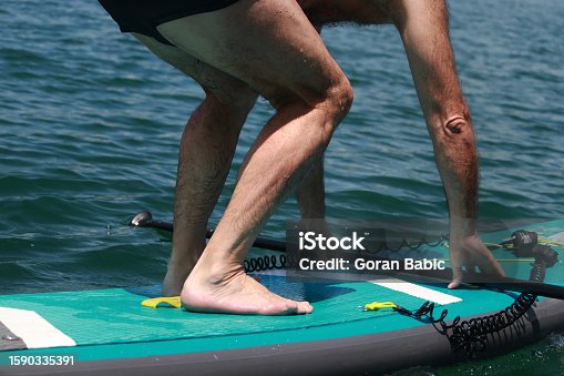 istock Man standing on surfboard 1590335391