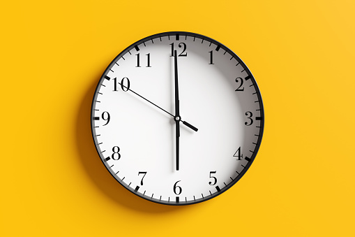Round black and white wall clock at almost 6 o'clock on yellow background. Illustration of the concept of wake up time and off duty time