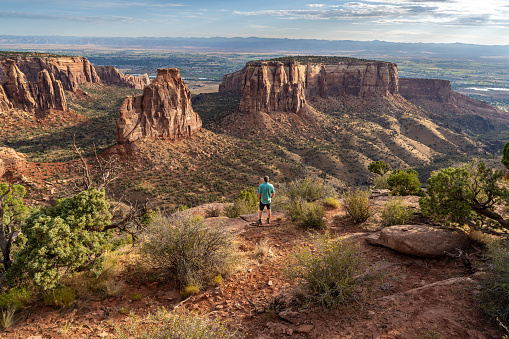 Mature Caucasian man, hiker, standing watching a natural occuring free standing pillar, Independence Monument, Colorado National Monument, Colorado
