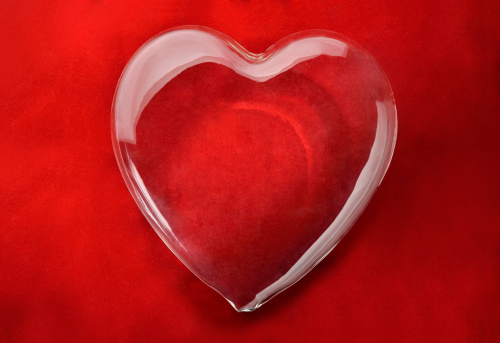 Empty glass heart on red background