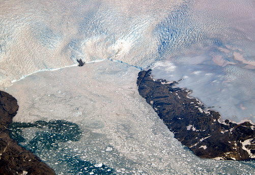 Isertoq, Sermersooq municipality, Greenland: glacier pouring ice into de North Atlantic ocean - melting Arctic ice in ocean water seen from the air. Rising sea level.