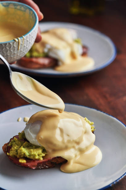 istock Poached Egg on Brown Bread Served with Ham, Avocado and Sauce Hollandaise 1590414283