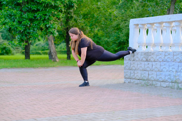 istock Plump girl doing muscle stretching exercises in the park 1590416932