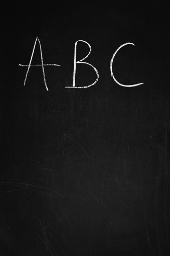 Chalk drawing on a blackboard. Letters ABC on wooden board. School chalkboard. Alphabet concept. Handwritten text. Preschool education. Knowledge concept. Language symbols with copy space.