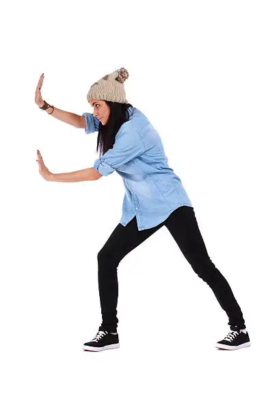 Teenage girl pushing something imaginary isolated over a white background