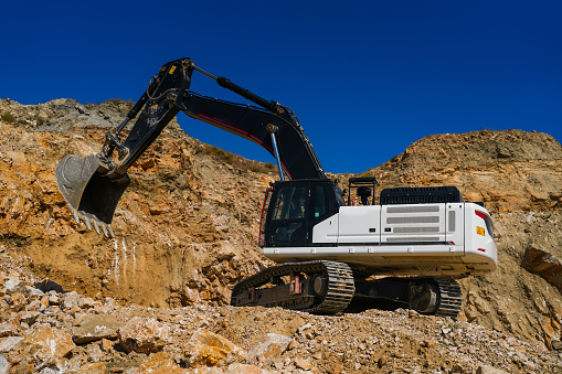 Hydraulic crawler excavator extracting stone in quarry at work