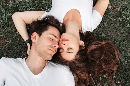 Top view of a young romantic couple lying in the grass