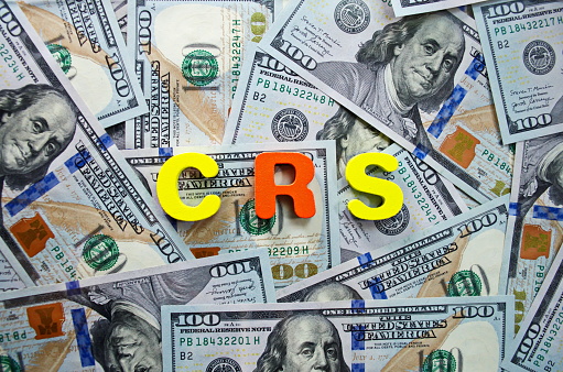 CRS Common Reporting Standard wooden letters text on background of dollar money Business concept analisys reporting standard sharing tax financial information Idea responsibility social life USA cash