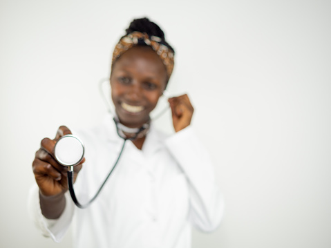 Young female doctor using a stethoscope while smiling. Looking at camera isolated on white background
