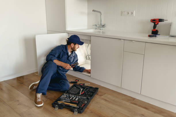 istock Professional plumber in blue uniform fixing broken water tap in kitchen. Repair service concept 1590540745