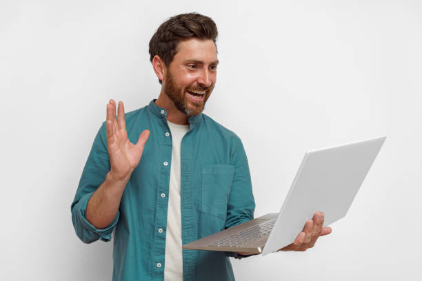 istock Handsome smiling man with laptop talking via video call over white background 1590549909