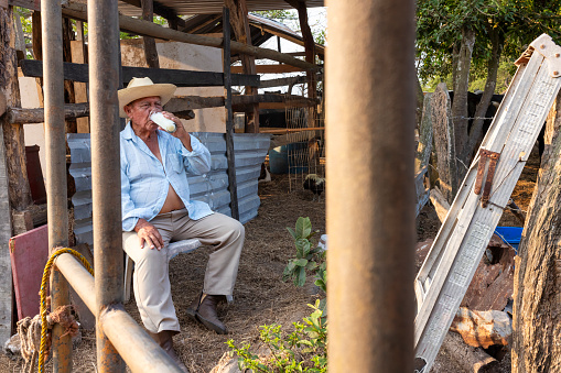Elderly man enjoying a glass of milk on his ranch