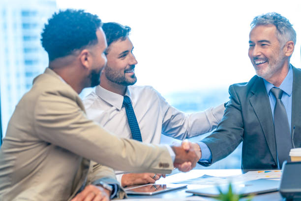 istock Businessmen shaking hands at the board room table. 1590584861