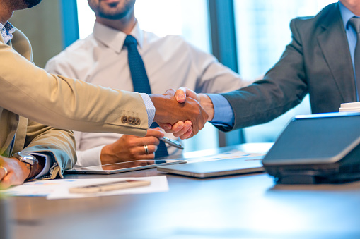 Businessmen shaking hands at the board room table.. They have just sealed a contract