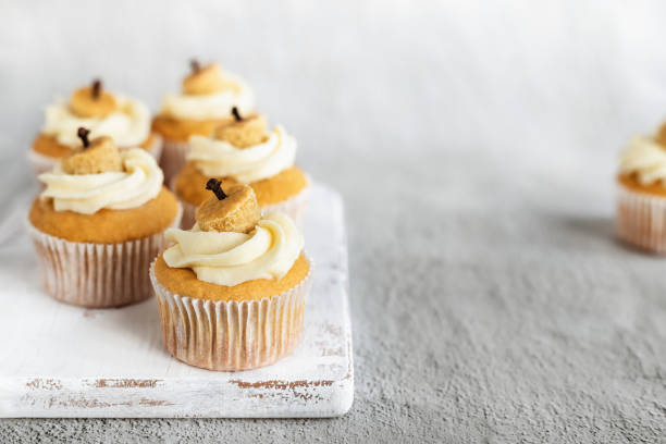 istock Pumpkin cupcakes with frosting on grey background 1590588013