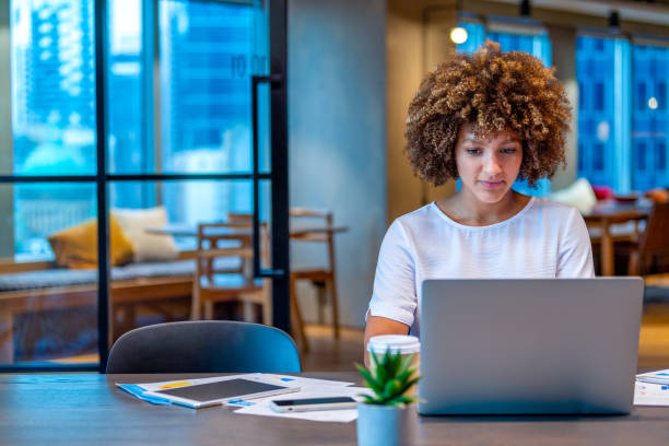 istock Young woman working on a laptop computer in a modern office. 1590592815