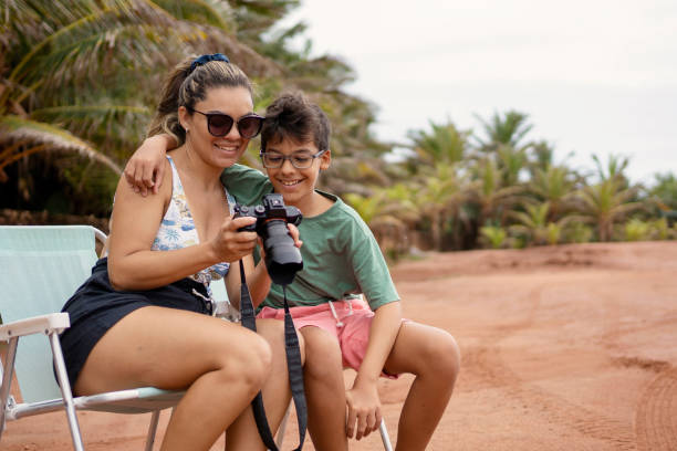 istock Mother and son using photographic camera on the beach 1590633374