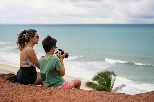 istock Mother and son using photographic camera on the beach 1590633584