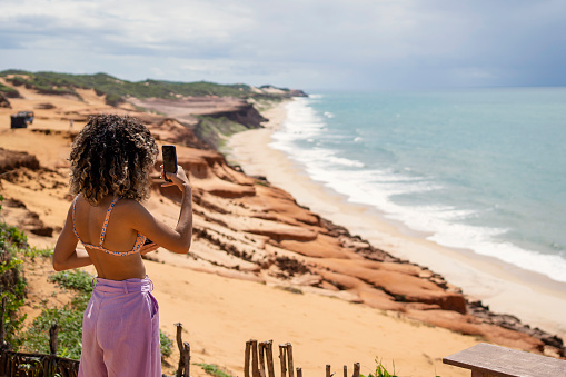 Young woman photographing the beach during vacations