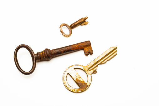 Three rusty keys over white background