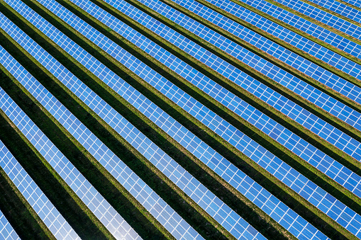Many rows of blue solar panels in a large solar power station viewed from above.