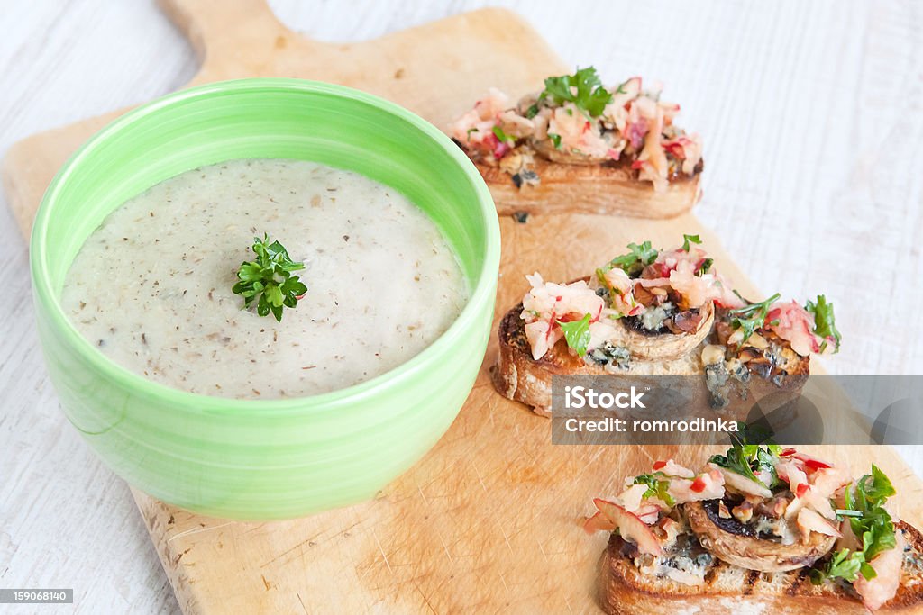 Fresh cream cauliflower soup with mushrooms Fresh cream cauliflower soup in green bowl with fresh baked bread with apples, mushrooms, cheese and parsley on wooden board Appetizer Stock Photo