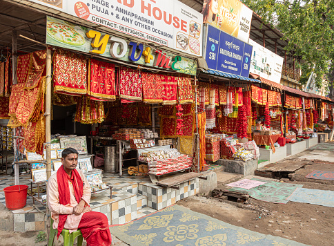 Guhawati, India - 10th April  2023: A vendor sits outside his stall, one of several selling Indian fabrics and sweetmeats on the road to the Kamakhya Temple, in the outskirts of Guhawati, Assam.