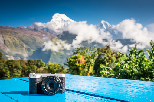Compact digital camera placed on a map in front of beautifaul snow-covered peak of mountain, Annapurna, Nepal