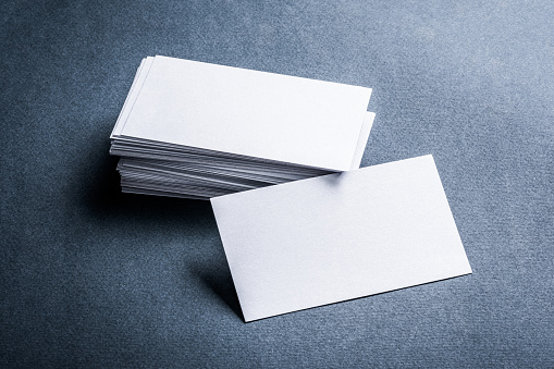 Two stacks of blank paper business cards on textured background.