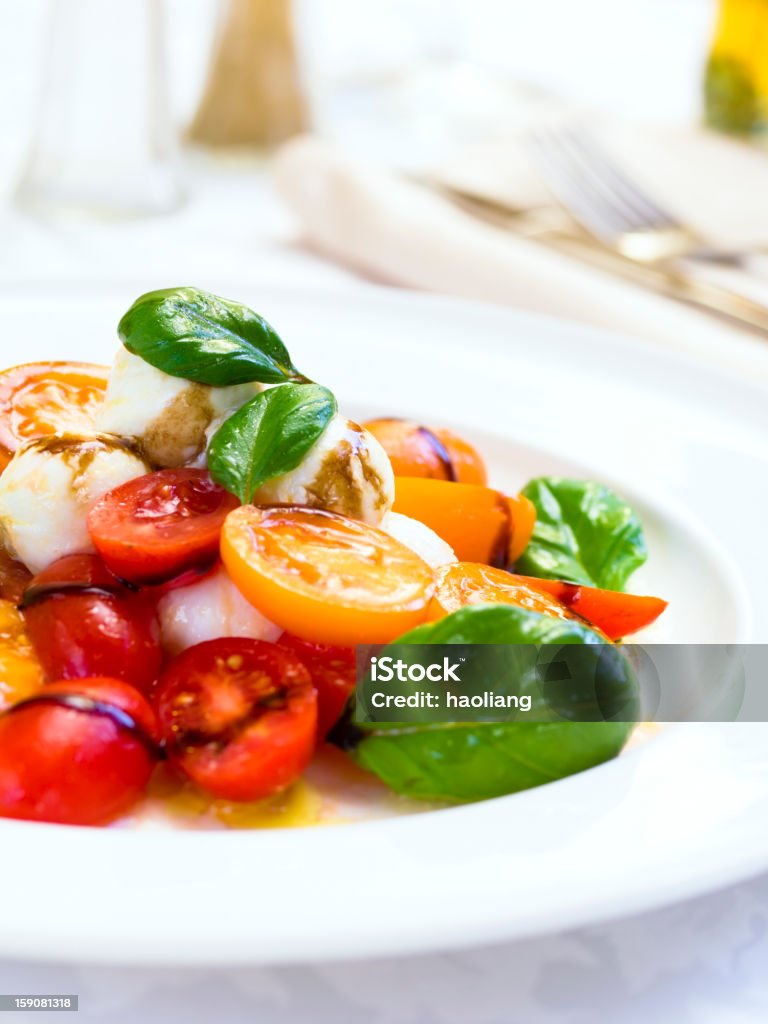 Close-up of a Tomato and Mozzarella Salad freshness Italy cherry tomatoes with mini mozzarella ball and basil leaves.olive oil and aged balsamic vinegar for dressing  Balsamic Vinegar Stock Photo
