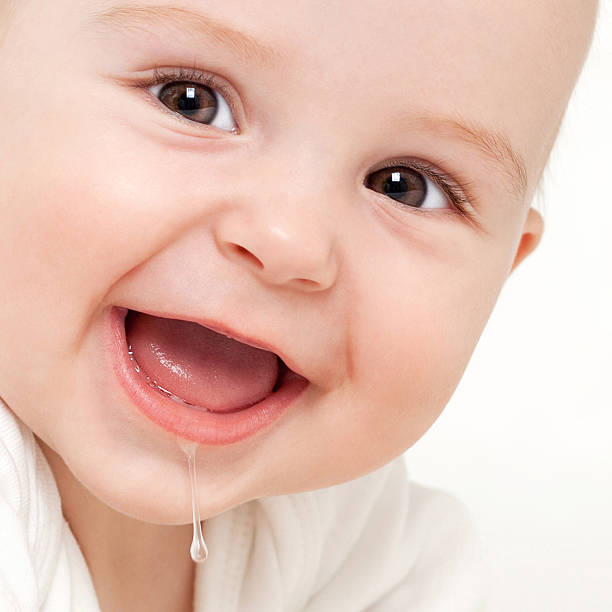 Growing first teeth Close up of an adorable baby drooling, on white background spit stock pictures, royalty-free photos & images