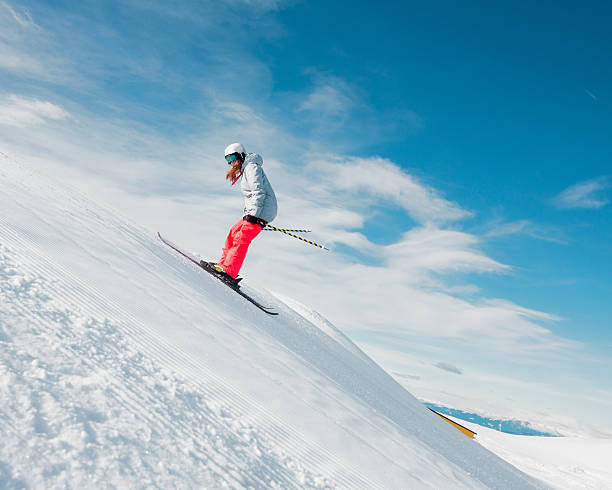 Free style skier Female free style skier. Skiing - jumping with rotation.. Snow skiing at high speed against blue sky back to front stock pictures, royalty-free photos & images